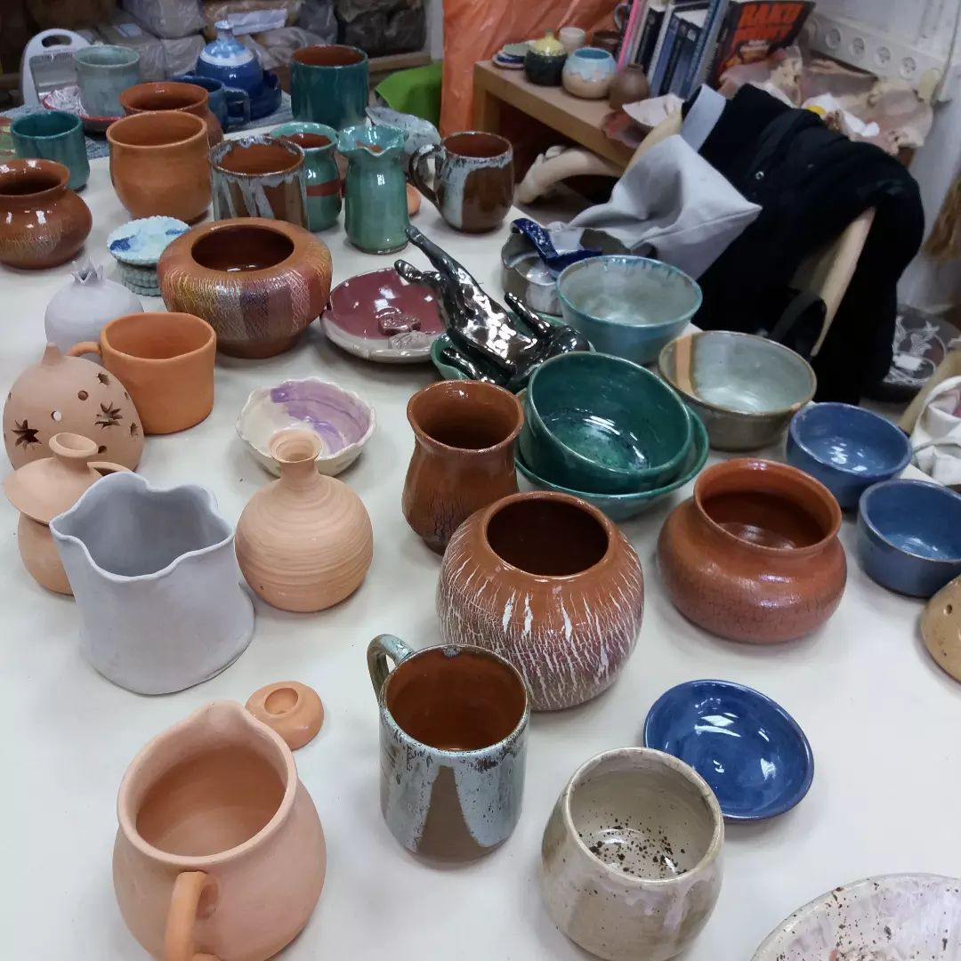 שולחן עמוס בכלי קרמיקה צבעוניים ומגוונים