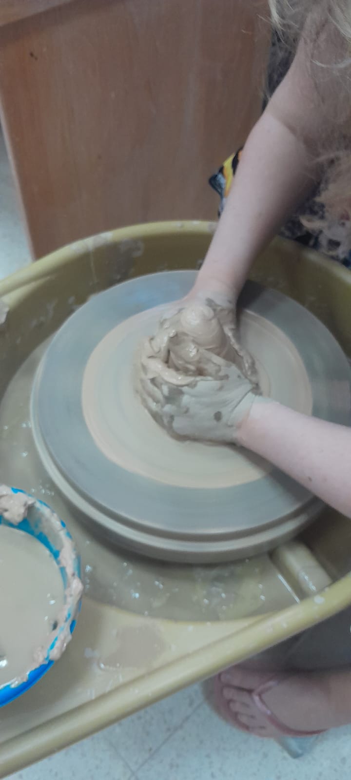 ידיים מעצבות יחד גוש חימר על אובניים מסתובבים