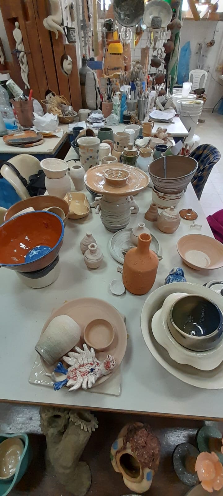 מבט עילי על שולחן עמוס בכלי קרמיקה מכל הסוגים והגדלים