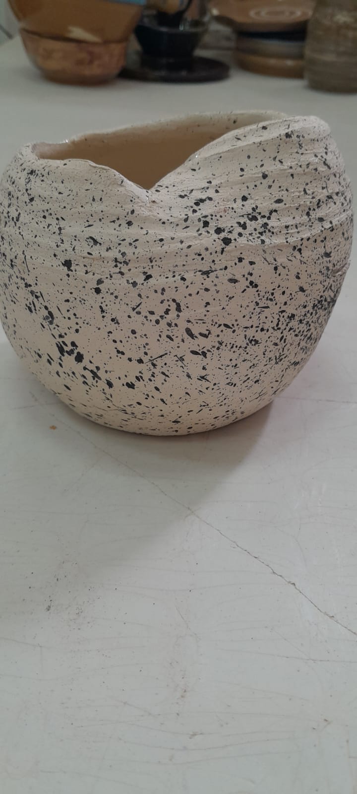 כלי קרמיקה עגול עם טקסטורת נקודות שחורות מותזות