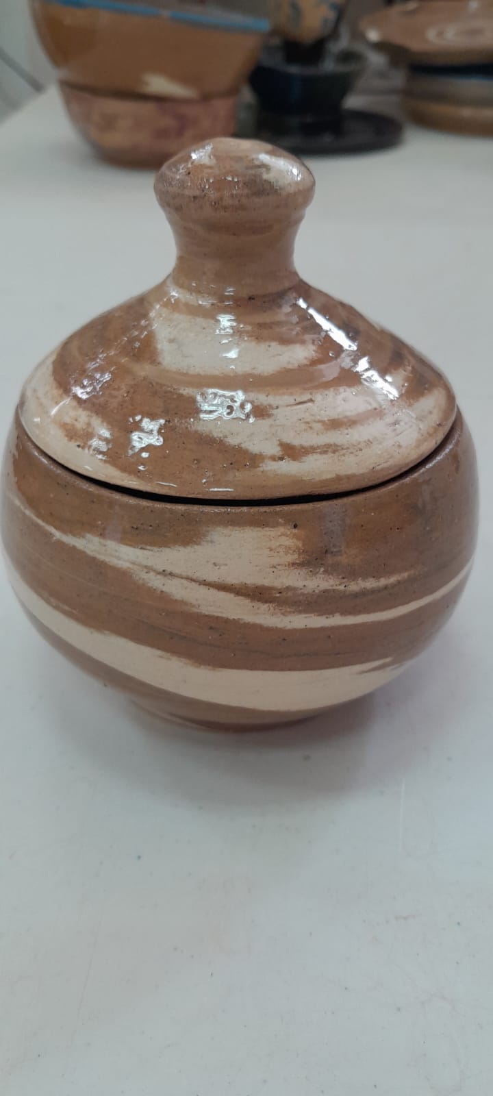 כלי קרמיקה עגול עם מכסה תואם ודוגמת פסים בגווני חום ולבן